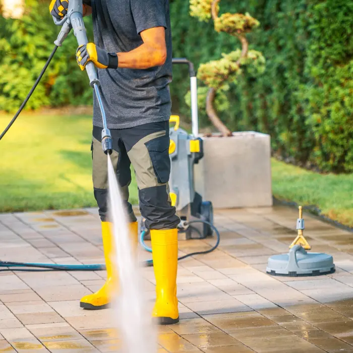 Person pressure washing patio tiles
